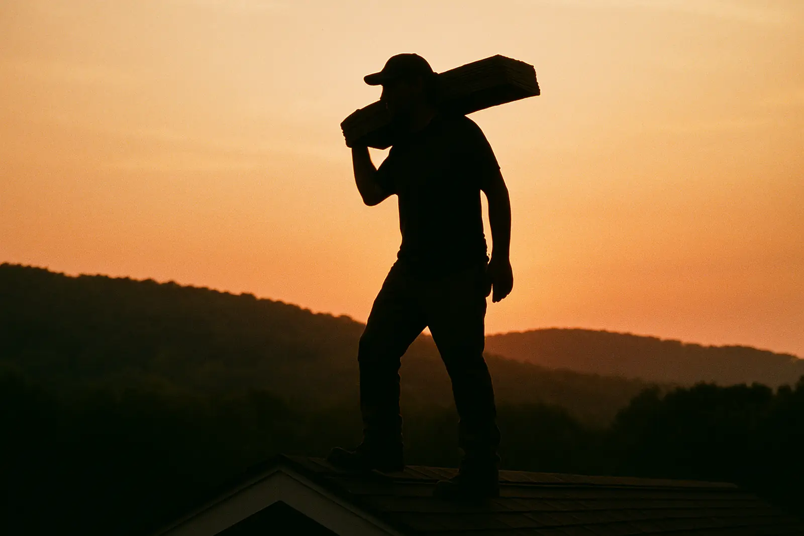 Roofer on a ridge line at sunset